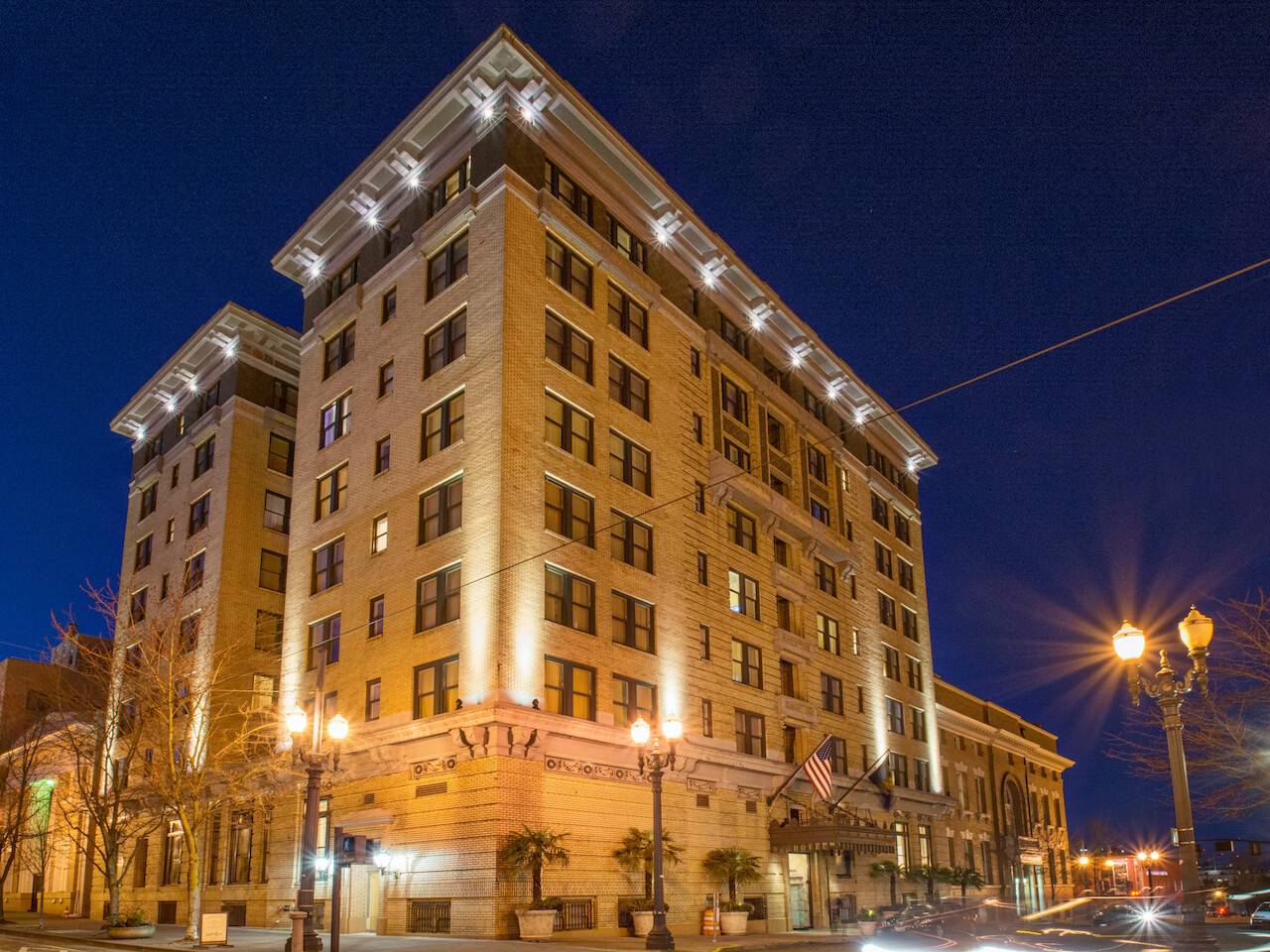 The image features a large, illuminated multi-story building at night, with streetlights and a clear sky in the background.