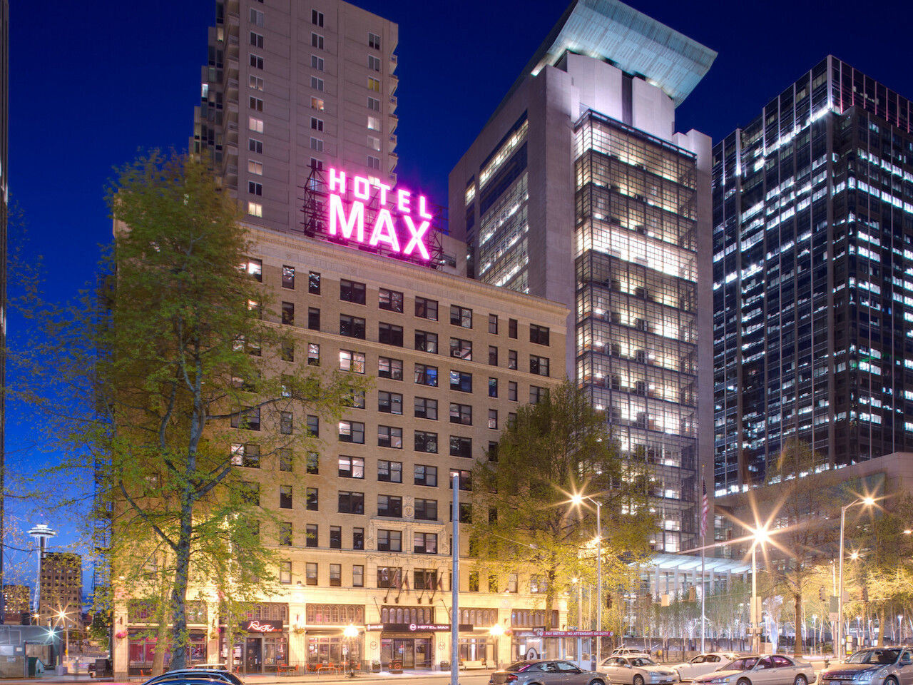 The image features an urban street scene at night with buildings, including one prominently displaying a &amp;quot;Hotel Max&amp;quot; sign in pink lettering.