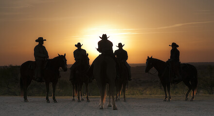 The image shows five people on horseback, silhouetted against a setting sun. They appear to be in a rural or desert landscape.