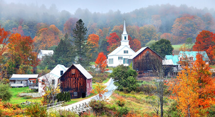 A picturesque village in autumn with colorful foliage, a white church, rustic barns, and a winding road amidst a misty, serene landscape ending the sentence.